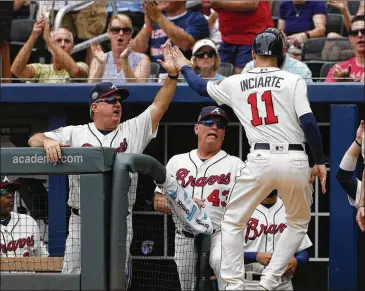  ?? JOHN BAZEMORE / ASSOCIATED PRESS ?? Ender Inciarte is greeted at the dugout by hitting coach Kevin Seitzer (left) and manager Brian Snitker (43) after scoring on Brandon Phillips’ double in the first inning.