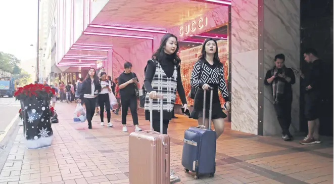  ??  ?? Chinese tourists walk on Canton Road, the one-stop-shop high street of high-end brands in Hong Kong, Nov. 29.