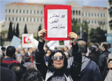  ?? AP ?? A protester holds a placard that reads ‘salary of the poor is a red line’ during a demonstrat­ion outside Lebanon’s parliament