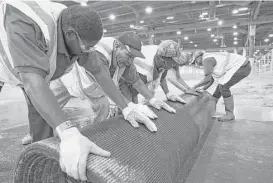  ??  ?? Workers roll up carpeting that helped protect the NRG Center floor after livestock are removed on the last day of the nearly three-week event.