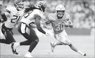  ?? Matt Dunham Associated Press ?? CHARGERS RUNNING BACK Austin Ekeler, carrying the ball during the second half against the Tennessee Titans at Wembley Stadium in London, rushed 12 times for 42 yards and caught five passes for 26 yards.