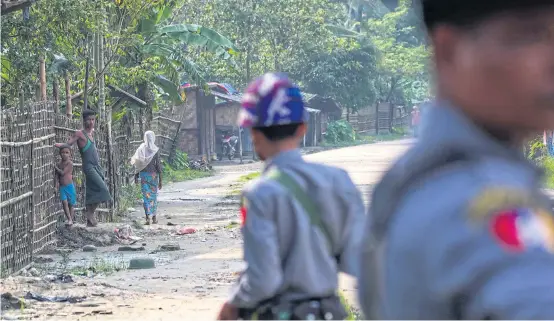  ?? AFP ?? Rohingya Muslims in the village of Shwe Zarr looking at Myanmar police, who are providing security due to recent nearby unrest, near Maungdaw township in Rakhine State on Wednesday.