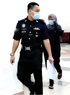  ??  ?? Afiqah accompanie­d by a police sergeant in the Kuching Court Complex.