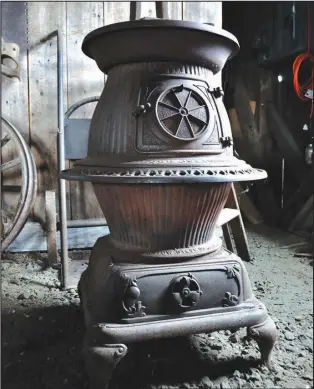  ??  ?? Graceful scrolled ironwork rings the potbelly of this antique woodstove in a blacksmith’s shop.