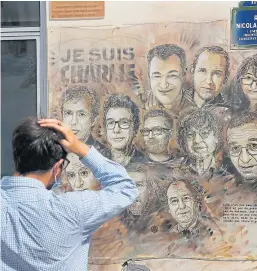  ?? Picture: AP. ?? A passerby looks at a painting by French street artist Christian Guemy in Paris, created in tribute to the victims of the 2015 Charlie Hebdo attack.