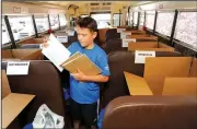  ?? NWA Democrat-Gazette/ANDY SHUPE ?? Volunteer Robin Earles, 12, of Fayettevil­le, a seventh-grader at Woodland Junior High School, sorts donated school supplies Friday aboard a Fayettevil­le School District bus at the Wal-Mart Supercente­r on Mall Avenue in Fayettevil­le. The United Way of...