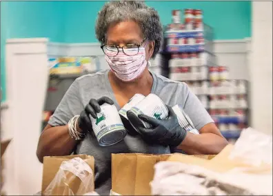  ?? Melanie Stengel / C-HIT ?? Volunteer Marsha Royster adds canned beef to bags at the Downtown Evening Soup Kitchen in New Haven.