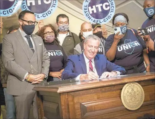  ?? ?? Mayor de Blasio signs law that requires owners of large hotels to pay workers who were fired due to the COVID pandemic. The Hotel Associatio­n of New York City, led by Vijay Dandapani (below), says that could further hurt an already struggling industry.