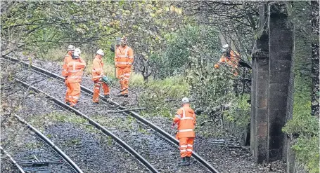  ?? Picture: SWNS. ?? Rail workers clear branches from the tracks near Markinch where a freight train hit a fallen tree.