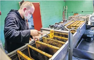  ?? [CHRIS LANDSBERGE­R/ THE OKLAHOMAN] ?? The Rev. Simeon Spitz uses a new honey extractor to extract honey from bee hives managed by St. Gregory's Abbey in Shawnee.