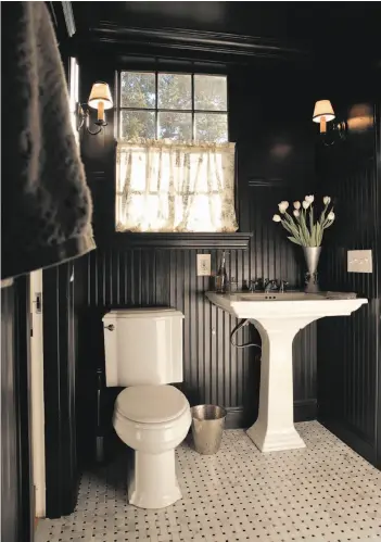  ??  ?? The first-floor bathroom in the Oakland home of Nathan Waldon and Tom Berkelman. The black walls, ceiling, window trim and moldings impart a sense of opulence that pairs well with the Carrara marble floor and shower tiles. The bead board carries over from the kitchen.