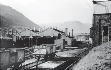  ?? W Potter/Kiddermins­ter Railway Museum ?? The eastern flank of Treherbert shed, including the lengthy row of offices, is recorded on 14 October 1962. A locomotive lurks within the shed, but the steam operations are drawing to a close. Without a crowded yard, the pit on the coal road is clear to see, along with two steel-bodied mineral wagons. For a time yet, visitors could happen upon steam and diesels in use together, but once the diesel-units were joined by English Electric ‘Type 3’ Co-Cos the days of steam, and of this shed, were limited and soon over. Redundant in March 1965, in 2021 the site is occupied by Everest Ltd.