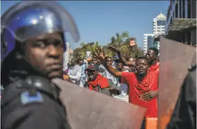  ?? Mujahid Safodien / Associated Press ?? Police patrol outside the Zimbabwe Electoral Commission offices as opposition supporters gather in the capital, Harare. At least three protesters were reported killed.