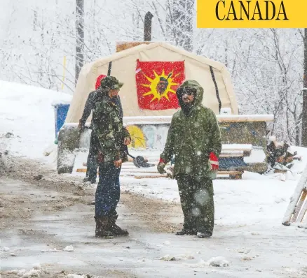  ?? RYAN REMIORZ / THE CANADIAN PRESS ?? Protesters stand near the entrance of a blockade of the rail line in Kahnawake Mohawk Territory, near Montreal, on Thursday.