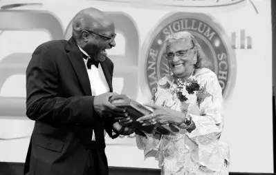  ??  ?? Wolmerian and radio personalit­y Francois St Juste presents a plaque to fellow Wolmerian and media veteran Alma Mock Yen.