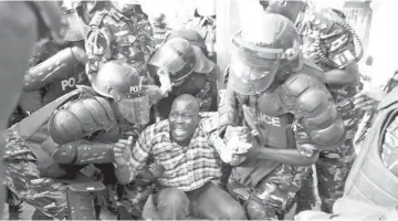  ??  ?? Riot police detain a supporter of Uganda’s leading opposition party Forum for Democratic Change as police and military forces disperse their procession with their presidenti­al candidate to a campaign ground in Kampala, Uganda. — Reuters photo