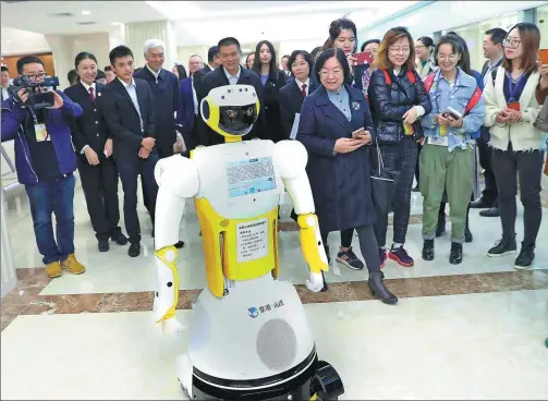  ?? ZOU HONG / CHINA DAILY ?? Xiao Fa, a robot assistant, is surrounded by officials during its first day at Beijing No 1 Intermedia­te People’s Court last month