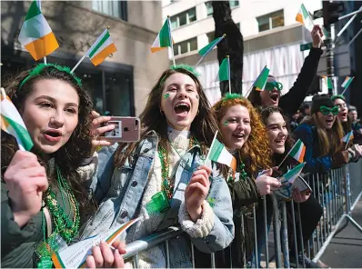  ?? AP Photo/Craig Ruttle ??    Spectators cheer as they take part in the St. Patrick’s Day parade Saturday in New York. Several bagpipe bands led a parade made up of more than 100 marching bands after Democratic Gov. Andrew Cuomo spoke briefly, calling it a “day of inclusion” and adding: “We’re all immigrants.”