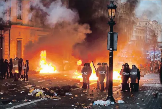  ?? ÀLEX GARCIA ?? Miembros de la Policía Nacional, delante de las barricadas de fuego que habían preparado grupos de manifestan­tes radicales