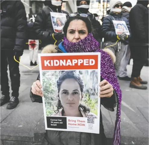  ?? PETER J. THOMPSON / NATIONAL POST ?? Maayan Shavit holds an image of her cousin Carmel Gat, who is a prisoner of Hamas in Gaza, at a Toronto rally
on Wednesday. Gat was visiting her parents near the Gaza border when Hamas terrorists attacked.