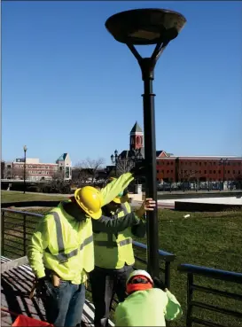  ??  ?? ABOVE: Benjamin Suttler (from left) Keegan Fletcher and Richard Calvert work on lighting fixtures on the rear patio of the Courtyard by Marriott on Wednesday.
Photos by Doug Walker, Rome News-Tribune