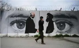  ??  ?? A man walks past a mural of the US special representa­tive Zalmay Khalilzad (left) and the Taliban co-founder Mullah Abdul Ghani Baradar in Kabul. Photograph: Wakil Kohsar/AFP via Getty Images