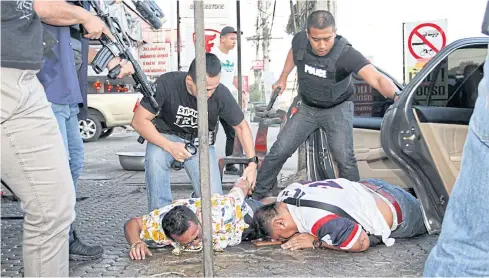  ??  ?? GOTCHA: Armed police officers from the Anti-Traffickin­g in Persons Division yesterday hold down two suspected members of a major drug-smuggling ring in Ayutthaya’s Wang Noi district. The men were caught with large quantities of marijuana.