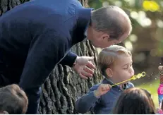  ?? JONATHAN HAYWARD/CANADIAN PRESS ?? Prince George plays with bubbles as Prince William looks on during a children’s tea party at Government House in Victoria.