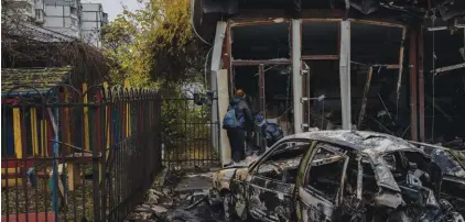  ?? Photos: Bernat Armangue/AP. ?? Residents check the damage of a shop destroyed a day earlier during a Russian attack in Kherson, southern Ukraine, Friday.