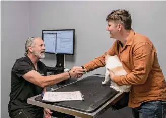  ?? Photos by Salgu Wissmath/Staff photograph­er ?? Dr. Andrew Greller at South Texas Veterinary Ophthalmol­ogy shakes hands with Travis Laechelin on Sept. 27 after administer­ing an eye exam to his dog, Alfonso.