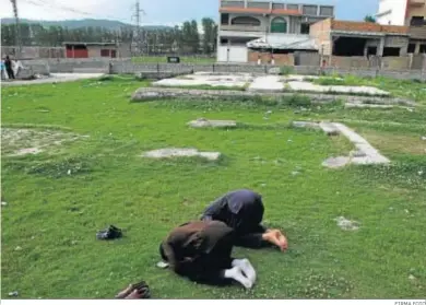  ?? FIRMA FOTO ?? Dos hombres rezando ante la vivienda donde fue asesinado Osama ben Laden, en Abbottabad.