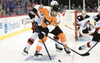  ?? ADAM HUNGER/AP ?? Flyers forward Elliot Desnoyers controls the puck in front of Devils defenseman Ryan Graves during the third period Saturday in Newark, New Jersey. It was Desnoyers’ NHL debut.