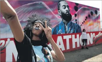  ?? Gary Coronado Los Angeles Times ?? CINDY LYNN of Los Angeles takes a photo with a mural of Hussle near his Marathon Clothing store.