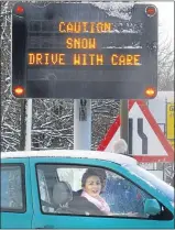  ??  ?? A motorist stops under a warning sign in Edinburgh during the snow alert