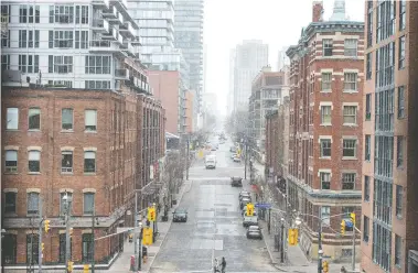  ?? PETER J THOMPSON / NATIONAL POST FILES ?? A couple walk across The Esplanade looking up a near empty Church Street in Toronto on Thursday.