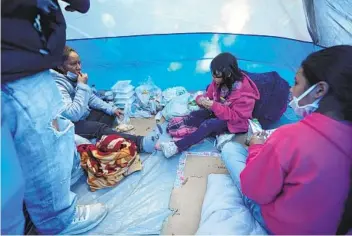  ?? ALEJANDRO TAMAYO U-T ?? A family seeking asylum eats lunch in their tent in the Chaparral Plaza in Tijuana on Wednesday. Volunteers from humanitari­an groups have begun serving free meals in the plaza.