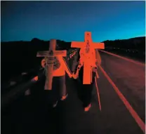  ??  ?? ABOVE: Brake lights illuminate the crosses carried by Melissa Moore and her dad, John Moore of Gallup, as they head to Chimayó just before sunrise Friday.