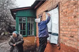  ?? DIMITAR DILKOFF/AFP VIA GETTY IMAGES ?? A woman covers broken windows Tuesday after shelling caused damage in Chasiv Yar, near Bakhmut, in eastern Ukraine.