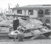  ?? JOEL ROUSE / MOD VIA AP ?? Hurricane Irma left a trail of destructio­n through many small Caribbean islands before attacking Florida on Sunday. Two men, left, look for belongings in the rubble of their restaurant Sunday on a beach in Orient Bay on the French island of St. Martin....