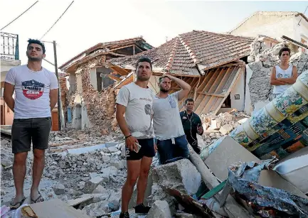  ?? GIORGOS MOUTAFIS ?? People stand among damaged buildings at the village of Vrissa on the Greek island of Lesbos after a strong earthquake shook the eastern Aegean.