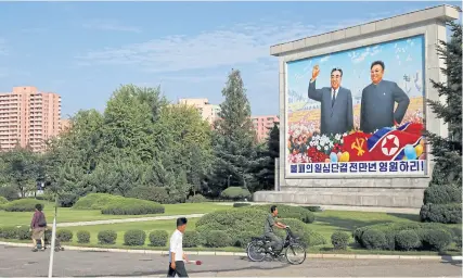  ??  ?? ABOVE Residents pass by a painting of late North Korean leaders Kim Il-sung and Kim Jong-il in Pyongyang.