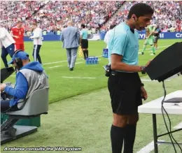  ??  ?? A referee consults the VAR system