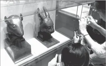  ?? LI XIN/ XINHUA ?? Visitors at the National Museum of China in Beijing view the bronze heads of a rabbit and a rat in 2013 that had been looted in 1890 and returned to China three years ago by a French businessma­n.