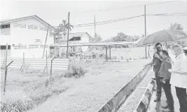  ?? ?? PERLU DINAIK TARAF: Ting (kanan) diiringi Effendi (dua kanan) ketika melihat keadaan pagar asrama SMK Lutong yang sudah rosak.