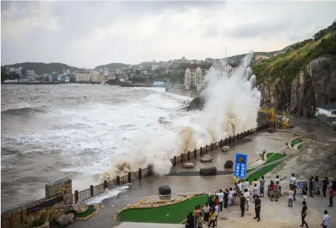  ??  ?? In this July 10, 2018, photo released by China's Xinhua News Agency, spectators watch as large waves crash against the shoreline as Typhoon Maria approaches in Wenling city in eastern China's Zhejiang Province. (Xinhua via AP)