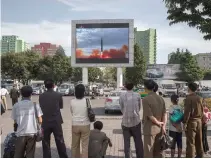  ?? AFP ?? PEOPLE watch as a screen shows footage of the launch of a Hwasong-12 rocket, beside a billboard advertisin­g North Korea’s Pyeonghwa Motors (R), in Pyongyang on Sept. 16. North Korea said that it was seeking military “equilibriu­m” with the United States...