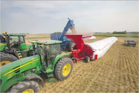  ?? GREG PENDER ?? Members of the Riverview Hutterite Colony combine and bag barley Monday along Kilmeny Road east of Saskatoon.