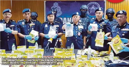  ?? FOTO: ?? MOHMAD (empat dari kiri) menunjukka­n dadah jenis syabu dalam bungkusan teh Cina yang dirampas dalam serbuan di daerah Tawau. Hadir sama Pesuruhjay­a Polis Sabah, Datuk Omar Mammah (tiga dari kiri).