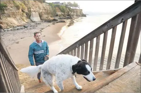  ?? Christina House Los Angeles Times ?? ROBERT WEAVER, known in the surfing community as “Wingnut,” and his dog go for a walk at Opal Cliffs, referred to as Privates Beach.