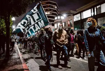  ?? Santiago Mejia/The Chronicle 2020 ?? Miko Tolliver, holding the Black Lives Matter flag, and Michael Fields march in a racial justice protest in 2020 in Oakland.